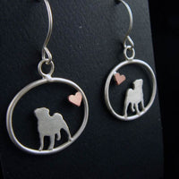 Sterling silver Pug dangle earrings with a small copper heart inside oval frames, matte finish on black background.
