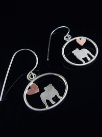 Sterling silver English Bulldog dangle earrings with copper heart inside oval frame, matte finish on reflective black background.