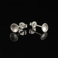 Sterling silver tiny cup studs with matte finish on black background