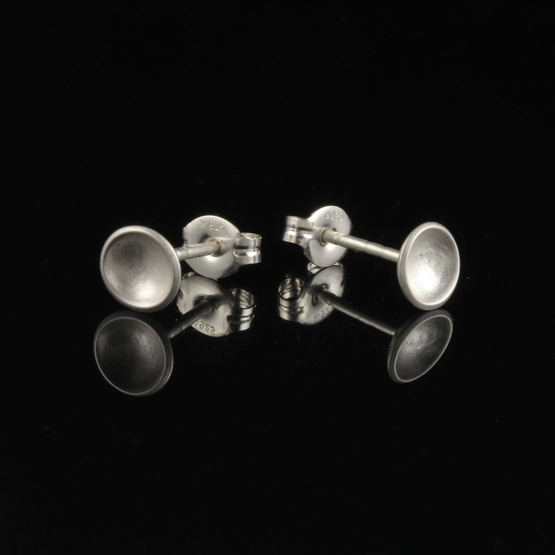Sterling silver tiny cup studs with matte finish on black background
