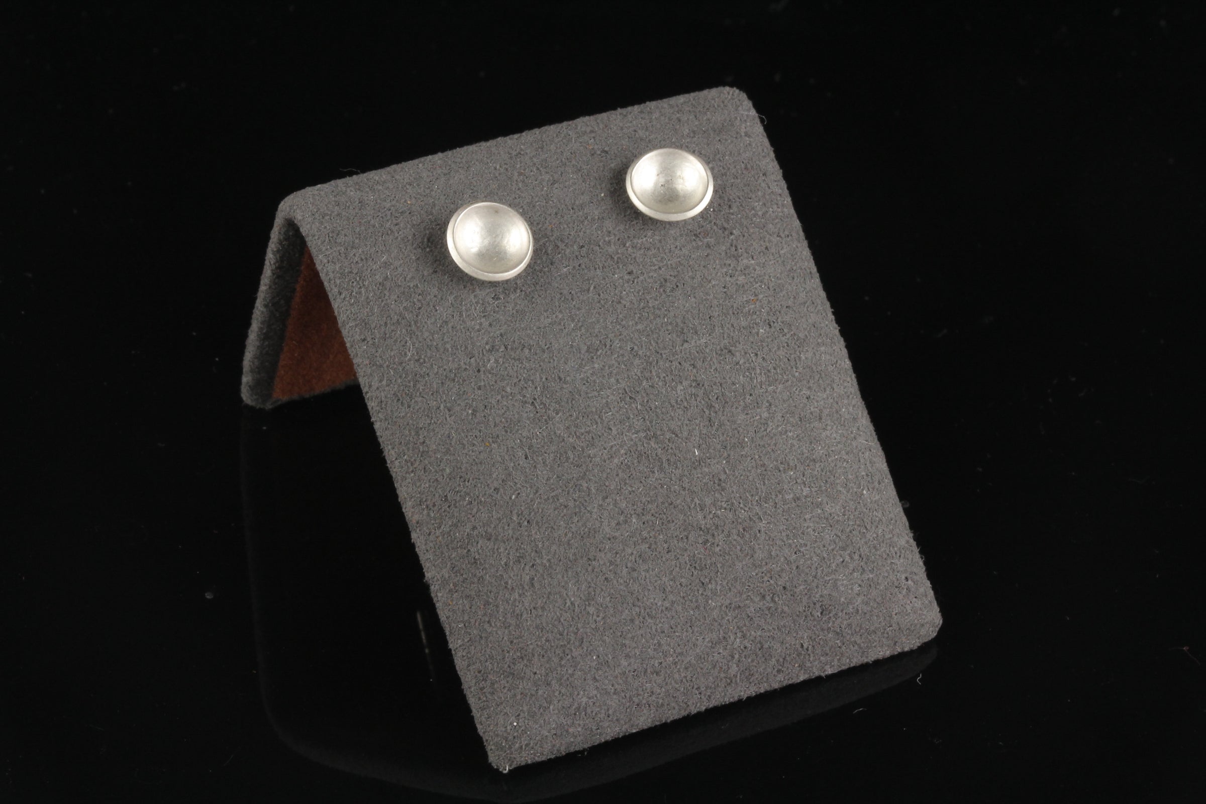 Handmade tiny domed cup sterling silver stud earrings - on display view
